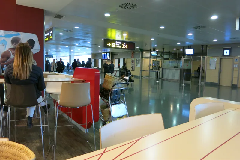 Travellers and signs pointing to boarding gates inside Ibiza Airport