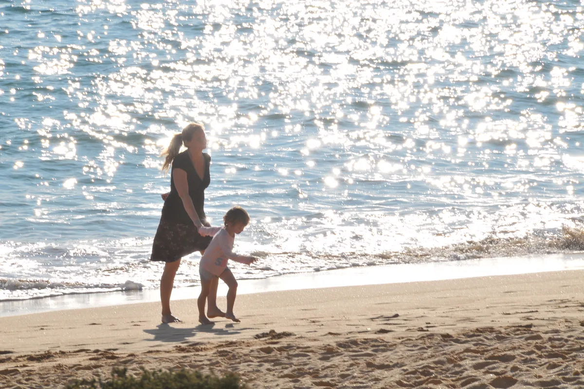 Mother and child walking together on a sunny beach