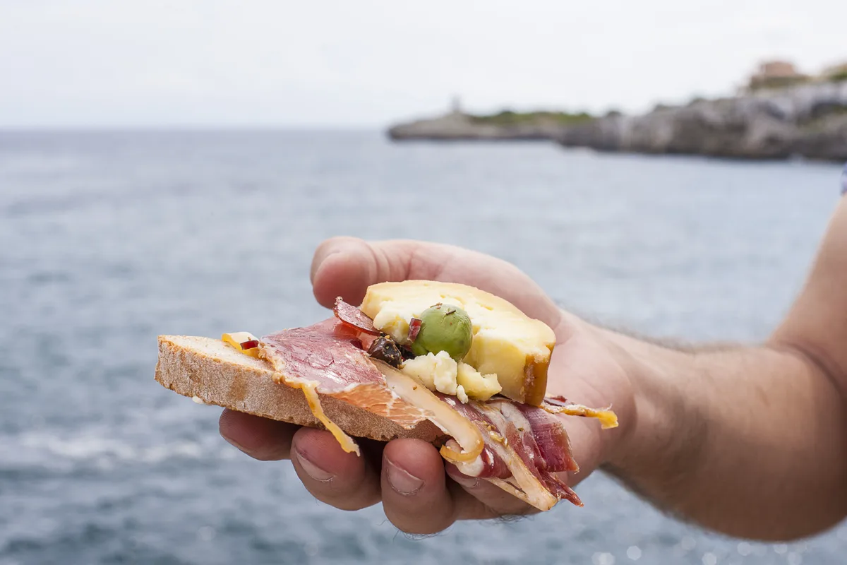 Bread with cured ham, cheese and olives by the coast of Mallorca