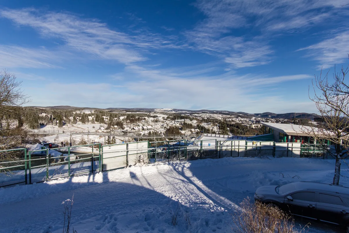 Snow-covered winter town and wooded hills beneath a blue sky